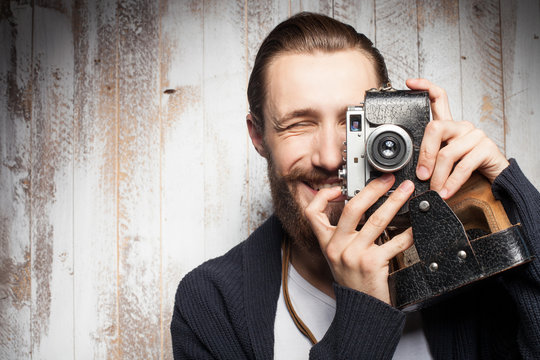 Cheerful young photographer with beard is making photos