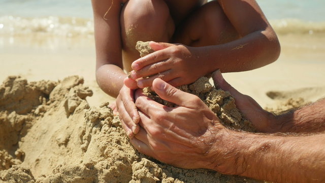 Family playing on the beach building sand castle. Close-up. 4K UHD.
