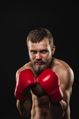 Athletic bearded boxer with gloves on a dark background