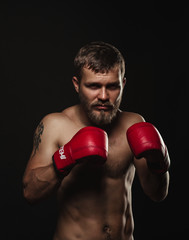 Athletic bearded boxer with gloves on a dark background - 91733960