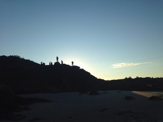 people's silhouette on top of cliff