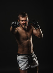 Obraz na płótnie Canvas Athletic bearded boxer with gloves on a dark background