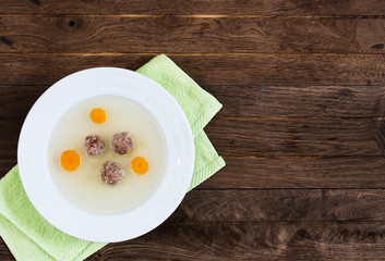 Plate of soup with carrot and meat balls on green towel