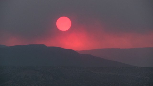 Time lapse shot as the sun sets behind a smoky red horizon.