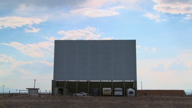 A shot of clouds passing over an abandoned drive in theater screen.