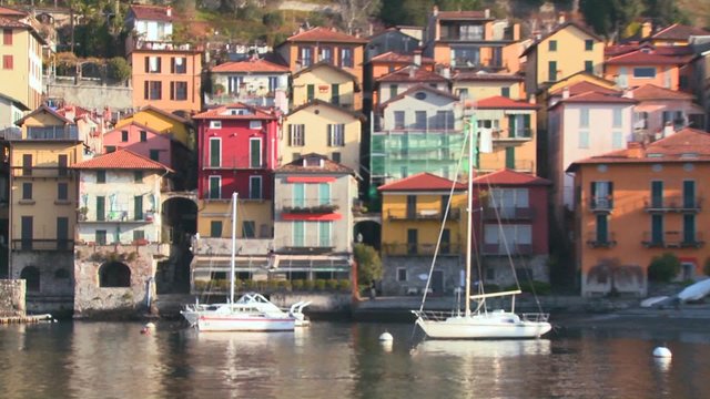 POV from a boat of the shores of Lake Como with the town of Varenna and the Italian Alps in background.