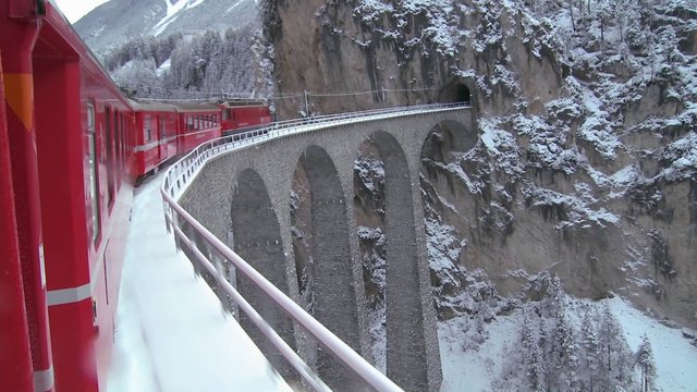 A train in Europe crosses a remarkable bridge and plunges directly into a tunnel.