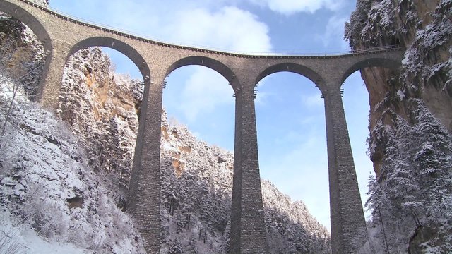 A train in Europe crosses a remarkable bridge and plunges directly into a tunnel.