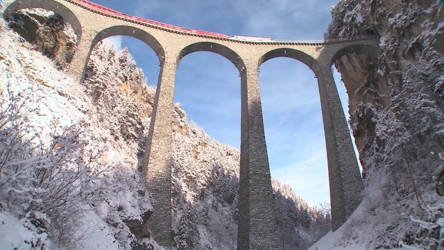 A train in Europe crosses a remarkable bridge and plunges directly into a tunnel.
