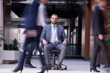Obraz premium business man sitting in office chair, people group passing by