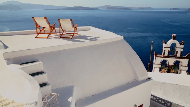 Pan across deck chairs sit on a beautiful balcony in the Greek Islands.