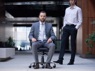 business man sitting in office chair, people group  passing by