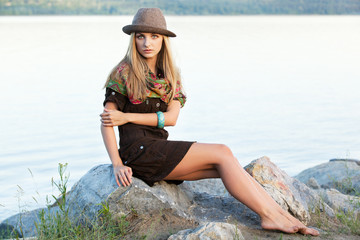 Young woman on stones near water