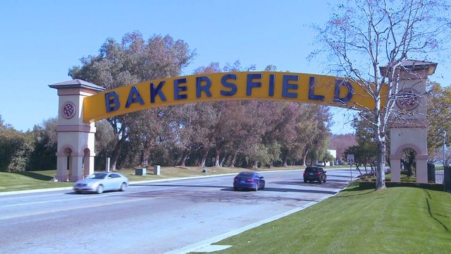 Cars drive into Bakersfield, California under the traditional arched gateway to the city.