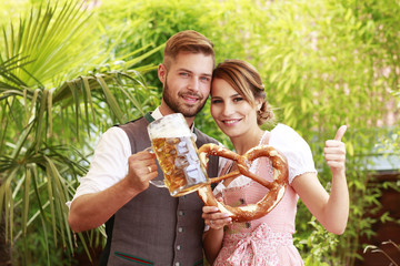 Glückliches bayrisches Paar in Tracht mit Bier und Brezn