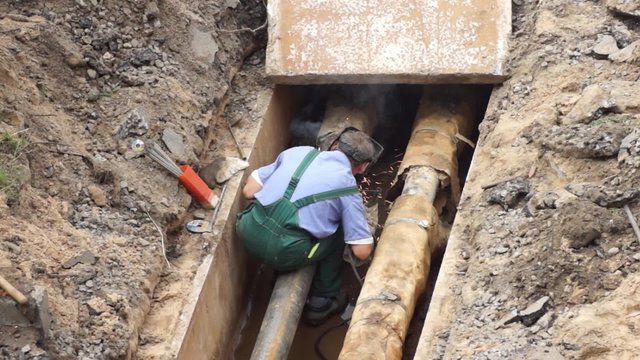Worker pipe weld heating pipeline, back view