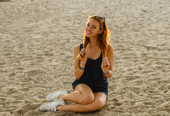 Fototapeta na wymiar Slim redhead female posing on a beach.