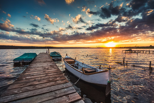 Peaceful sunset with dramatic sky and boats and a jetty