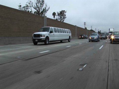 A stretch limo drives down a freeway.