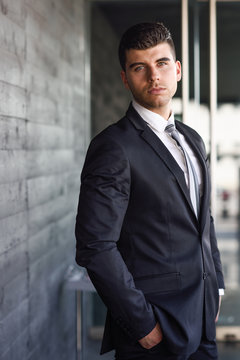 Young businessman near a office building wearing black suit