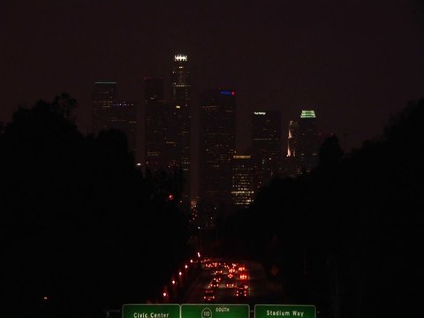 A time lapse of vehicles driving on the freeway and into the city at night.