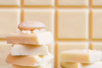 White chocolate with almond. Bar of chocolate in the background.