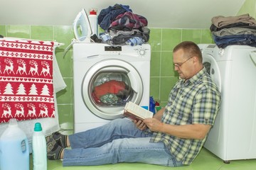 A man washes clothes in the washing machine. Housework men. Man helping his wife when washing...