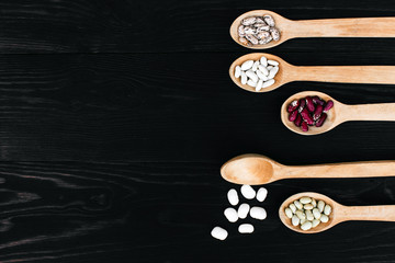 A colorful of beans in wood spoon on wood background