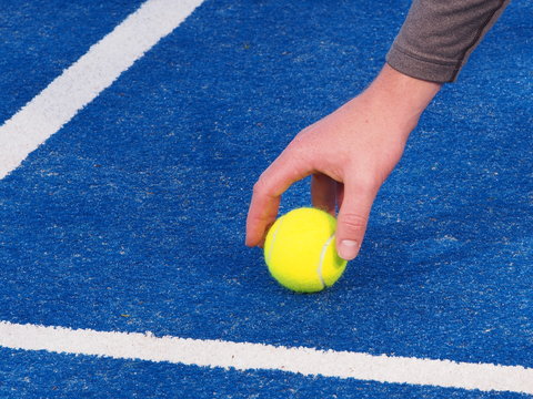 Hand of a ball kid picking up a Tennis ball from a blue artificial grass court, Melbourne, Australia 2015