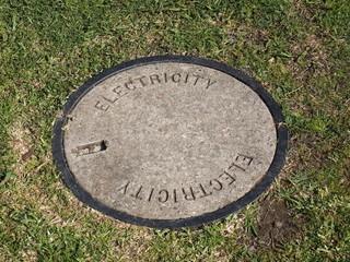 Round concrete lid on a electrical pit on a nature strip marked with Electrical, Melbourne, Australia, 2015