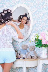 Adorable trendy woman posing in front of a mirror in hair curlers