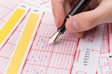 m&auml;nnliche Hand F&uuml;llt Lottoschein