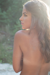 Backview of sexy girl topless covered by hands in countryside