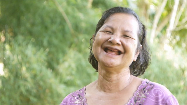 60 years old thai woman,no teeth, laughing happily in garden