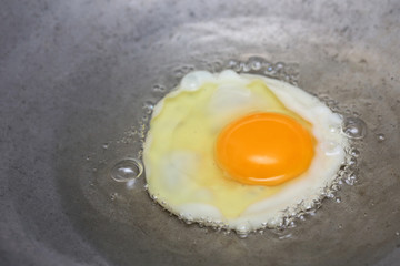 cooking fried egg in hot pan with oil