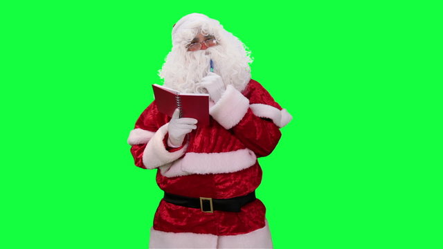 Santa Claus with Notepad in hand chroma key (green screen). Santa makes notes in a red notebook isolated on green
