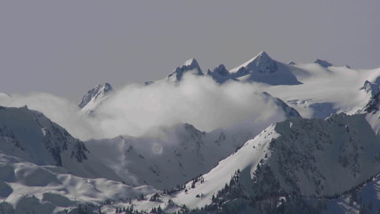 A time lapse shot of clouds over a snowy mountain.