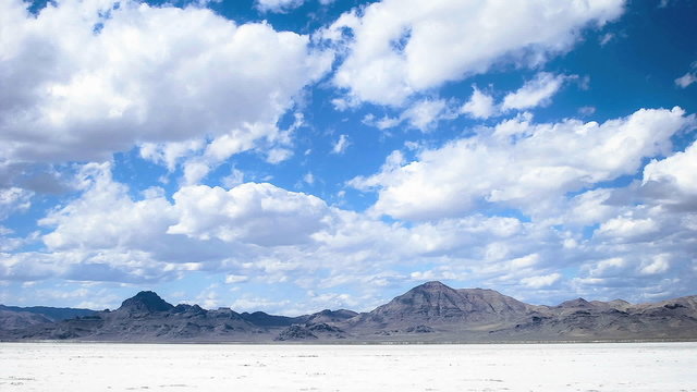 Time lapse of clouds moving over salt flats or desert.