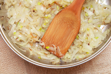 fried onions with a wooden spatula