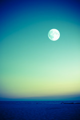 Naklejka na ściany i meble Full moon over beach at dusk