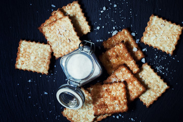 Saltine crackers and salt on a dark background, top view, select