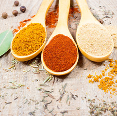 Spice powder on a wooden background. Closeup on paprika, curry and ginger.