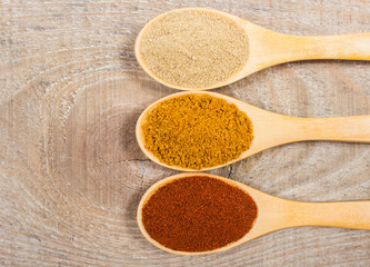 Spice powder on a wooden background. Closeup on paprika, curry and ginger.