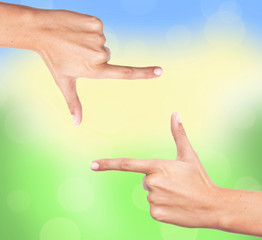 Finger frame over bright nature background