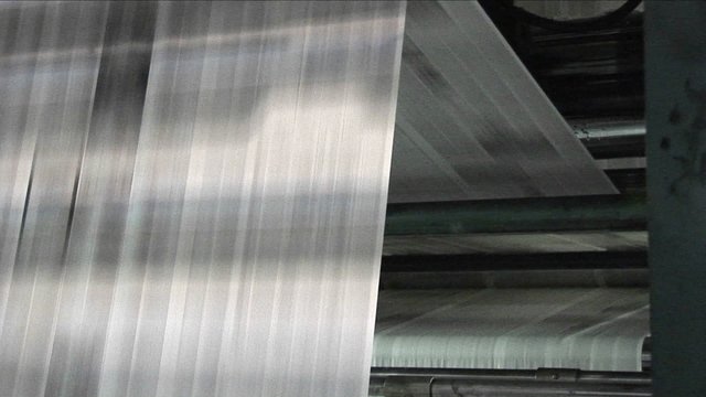 Newspapers move along an assembly line in a factory.