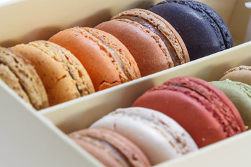 traditional french sweet dessert colorful delicious macarons in a rows in a box on wood background focus on red and green
