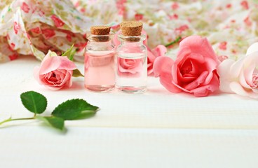 Fresh organic rose water eco beauty treatment flowers bottles wooden backdrop pink creamy tones...