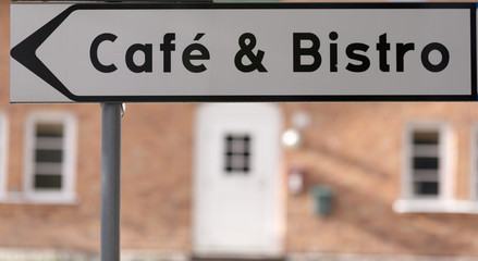 A café and bistro sign with a brick wall in the background
