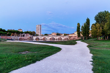 Rimini city park. Sunset time. Evening on tiberius bridge in bac