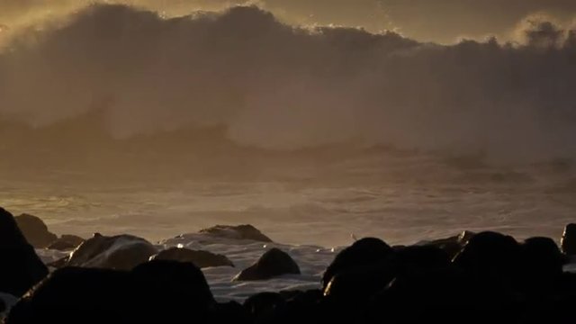 Beautiful large waves break against a rocky shore in Hawaii.